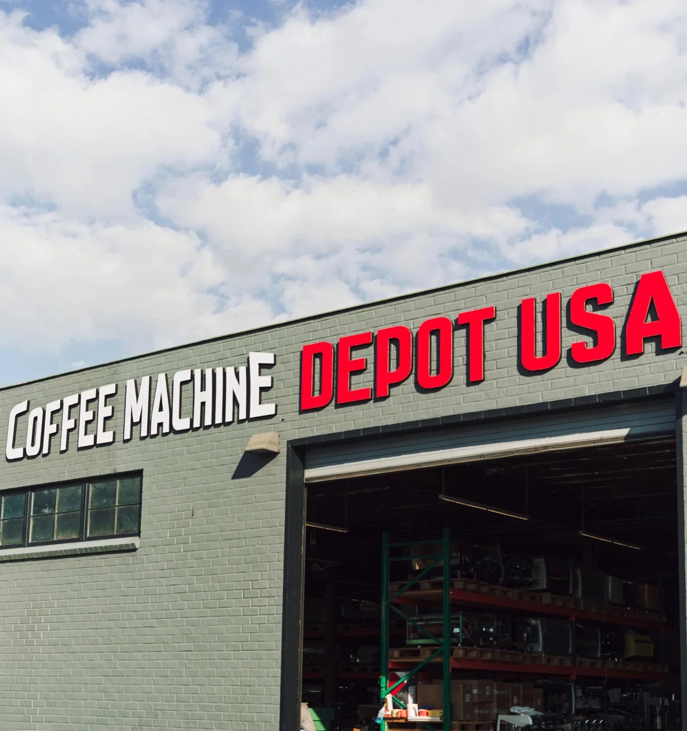 Exterior of Coffee Machine Depot USA warehouse with large red and white signage above an open garage door.
